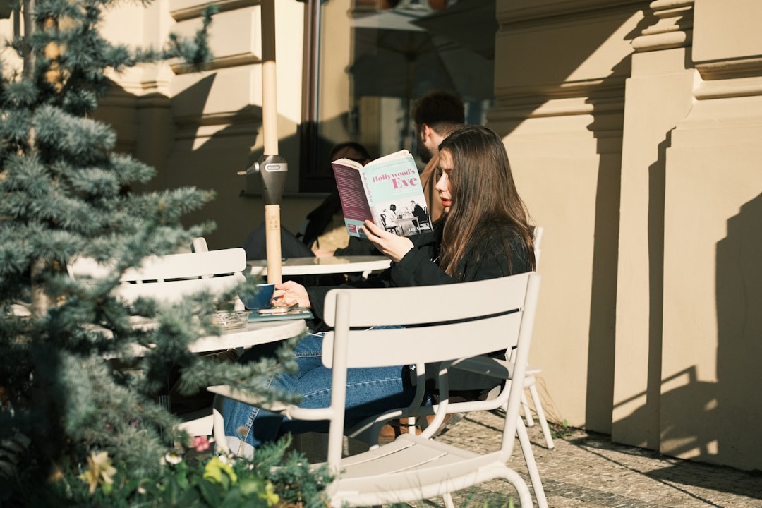 Young woman reading a book at an outdoor cafe.
