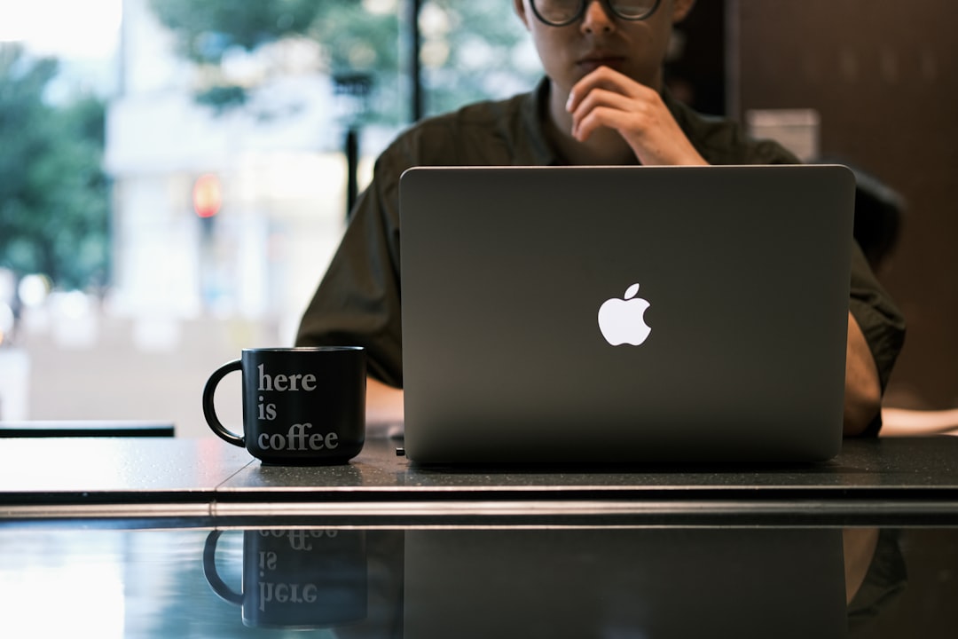 a person sitting at a table with a laptop and a watch