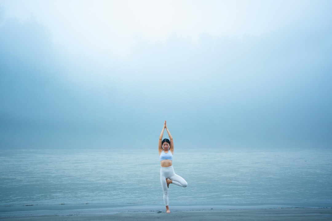A woman standing on one leg on a beach